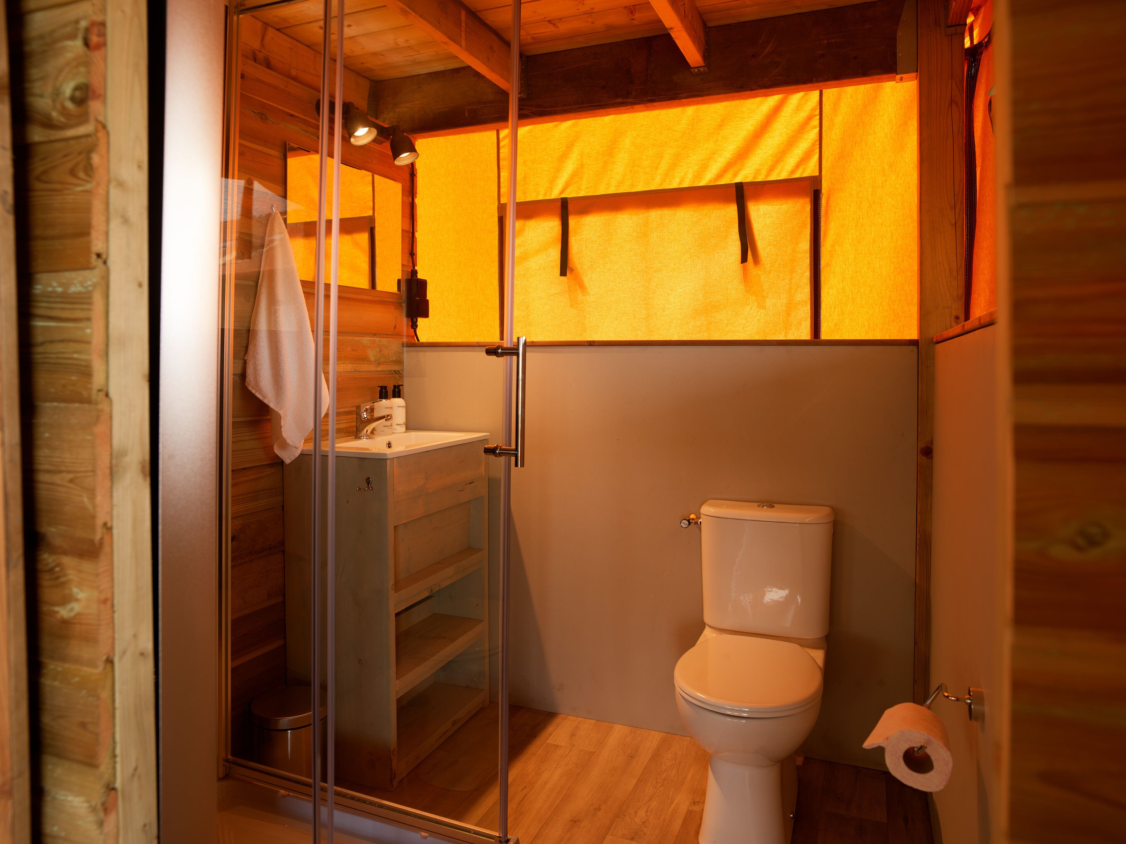 A bathroom with a glass shower enclosure, a toilet, and a sink.