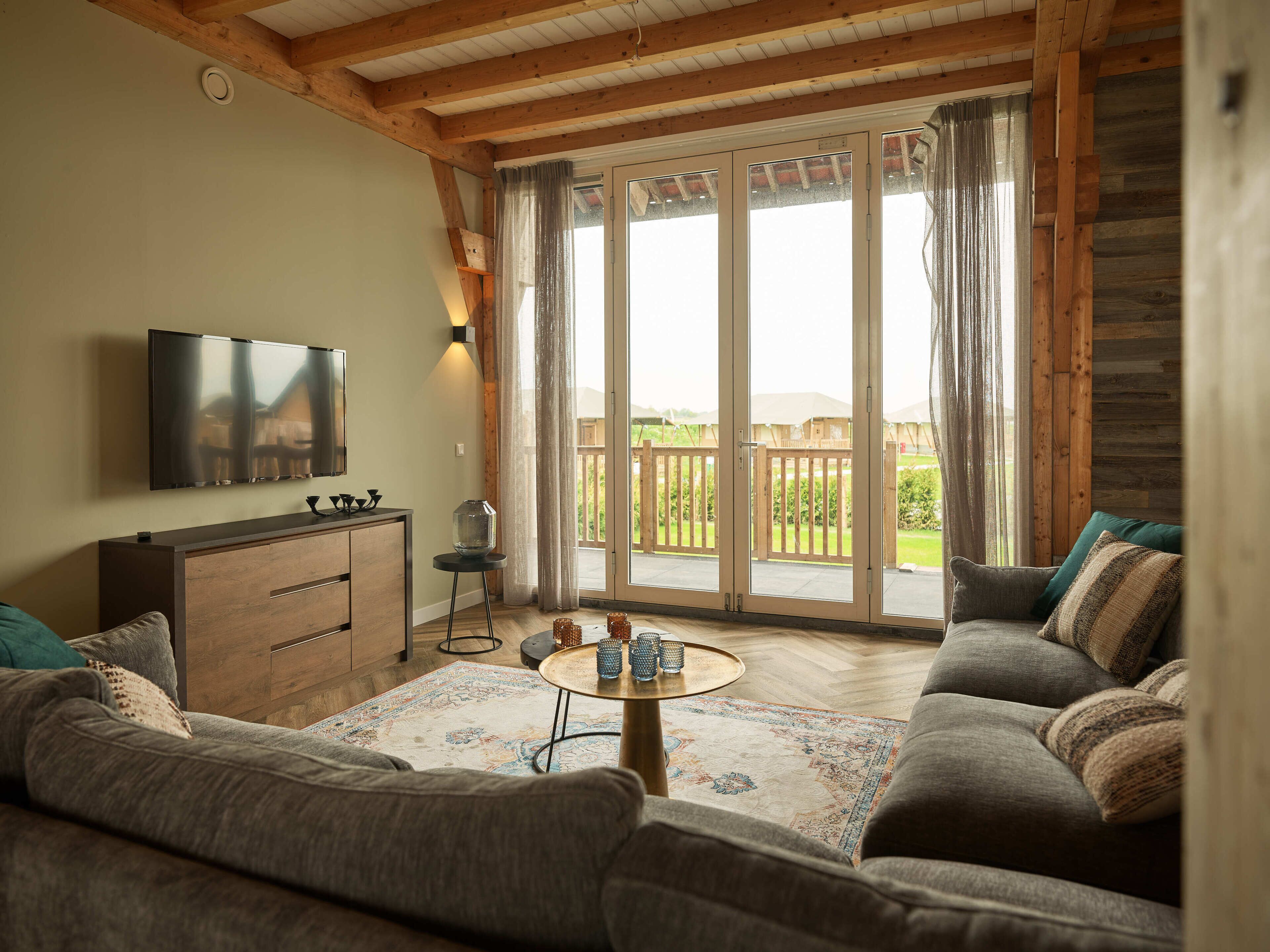 Un salon avec un canapé, une table basse, un téléviseur et une vue sur un balcon.