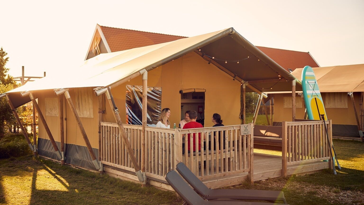 A tented accommodation with a covered deck and lounge chairs.