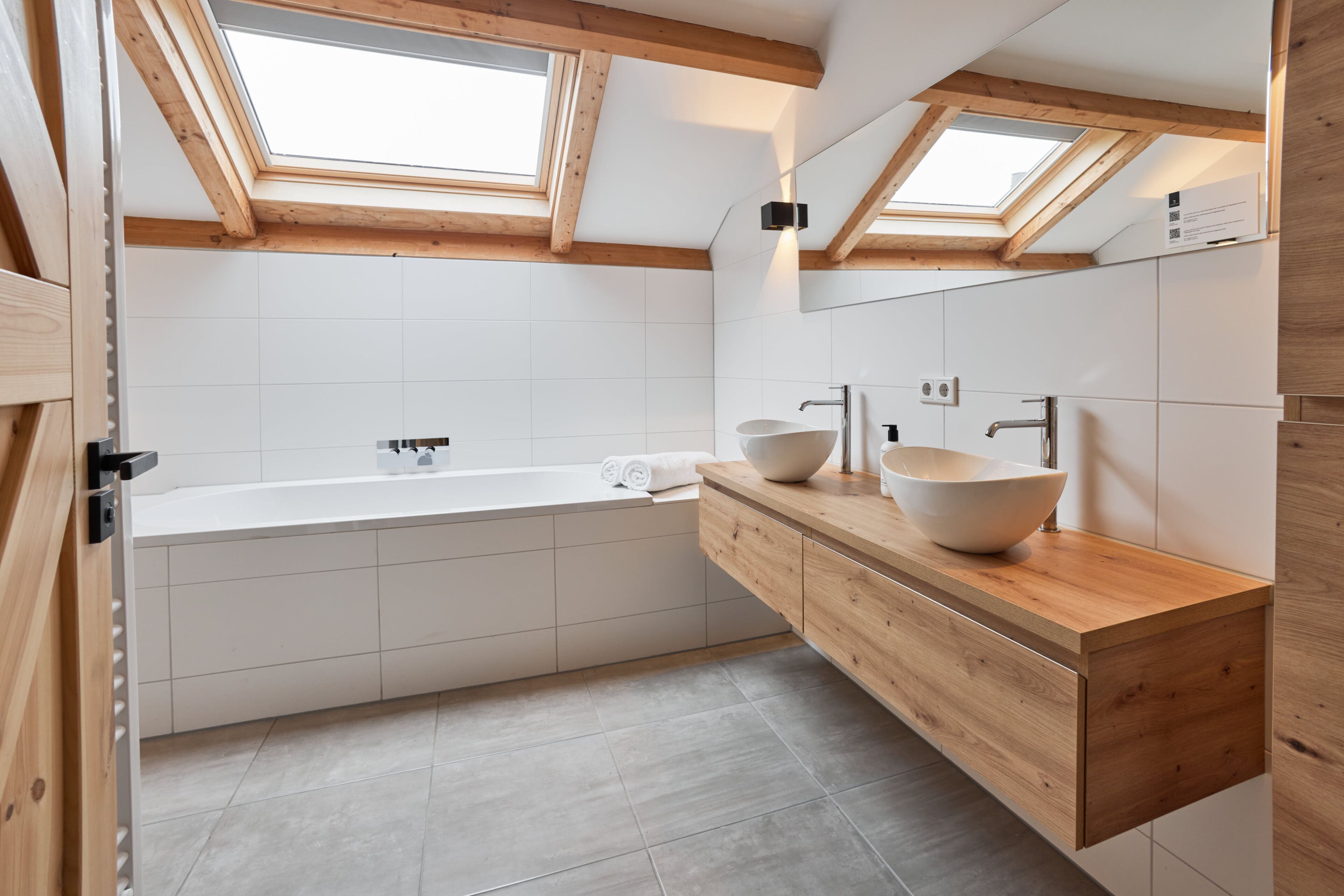 A modern bathroom with a freestanding bathtub, wooden vanity, and skylights.