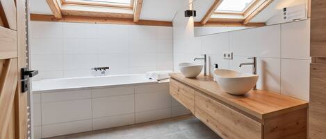 Ein modernes Badezimmer mit freistehender Badewanne, Holzwaschtisch und Dachfenstern.