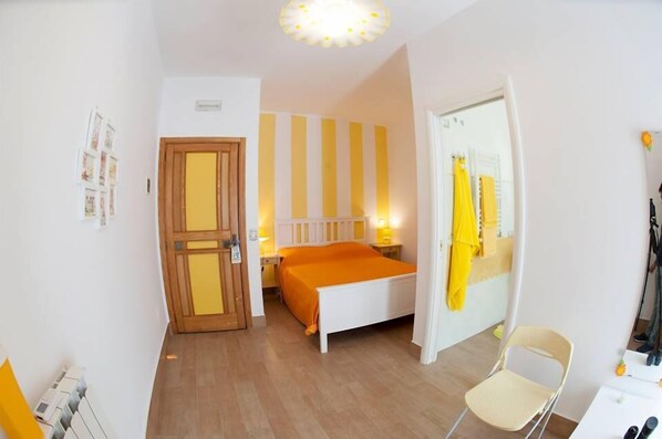 A bedroom with a bed, a chair, a door, and a wall with vertical stripes. - B&B O'paese e Masaniello (Naples)
