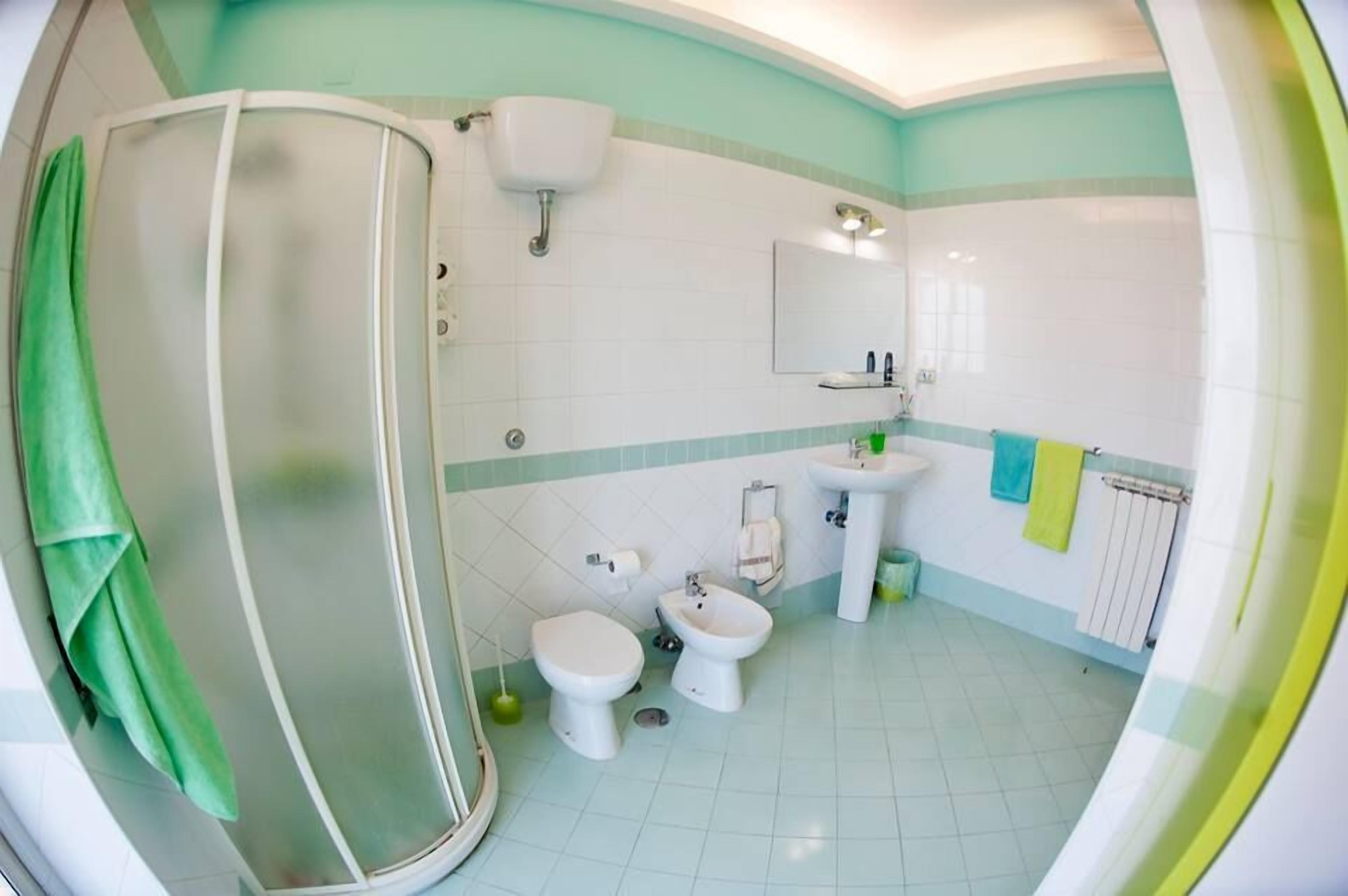 A bathroom with a shower, toilet, bidet, and sink.