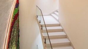 A modern staircase with glass railings and a textured wall with a butterfly design. - Playsales Scarlet (Indore)