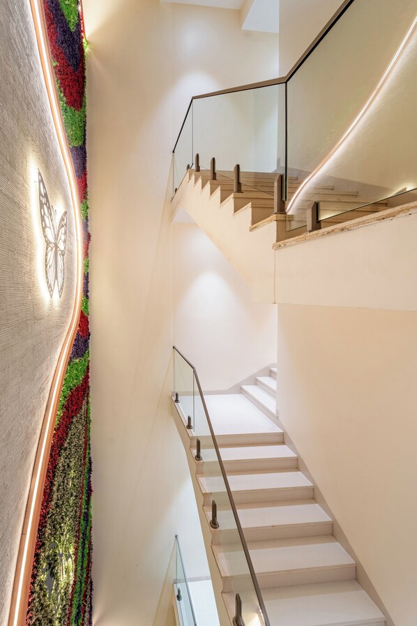 Un escalier moderne avec des rampes en verre et un mur texturé orné d’un motif de papillons.