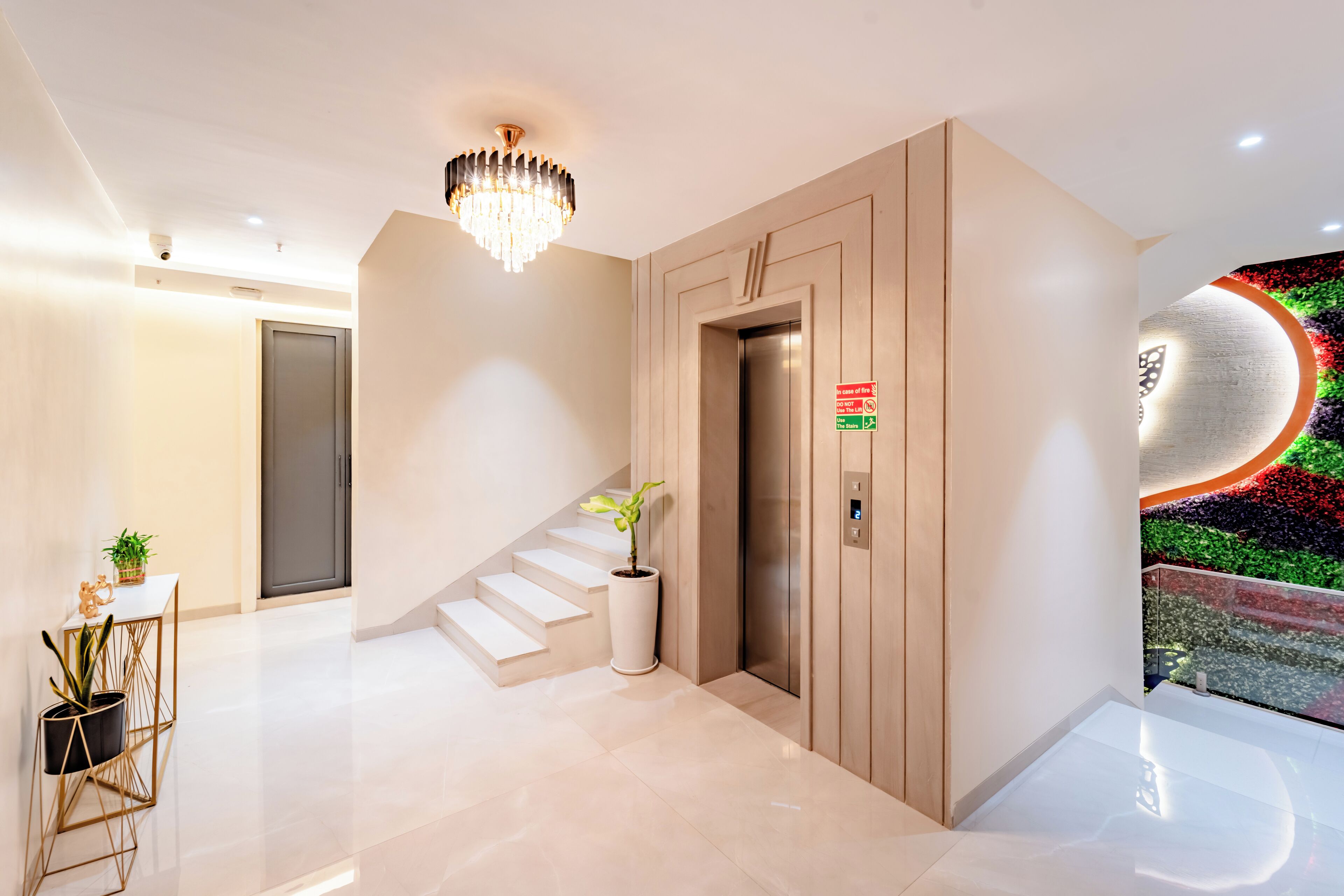 A modern hotel lobby with a staircase, elevator, and a decorative wall.