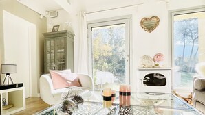 A spacious living room with a glass coffee table, a white sofa, and a green cabinet. The word "JARDIN" is visible on the wall. - Villa with swimming pool in the heart of Provence, in a half-hectare park (Ménerbes)
