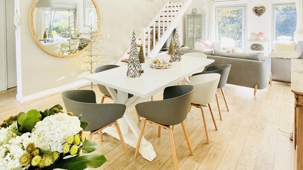 A modern dining area with a white table, grey chairs, and hanging pendant lights. A staircase with a white railing is visible in the background. - Villa with swimming pool in the heart of Provence, in a half-hectare park (Ménerbes)