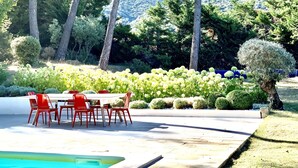 A poolside area with a table and chairs, surrounded by lush greenery and trees. - Villa with swimming pool in the heart of Provence, in a half-hectare park (Ménerbes)