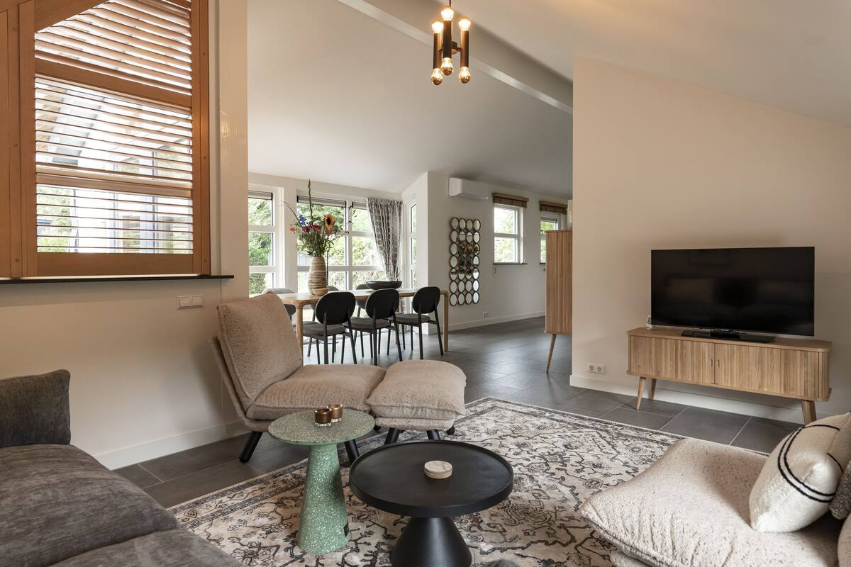 Un salon spacieux avec un canapé, une table basse et un téléviseur posé sur un meuble en bois.
