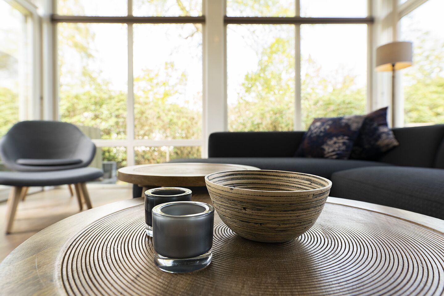 A modern living room with a round table, two glasses, and a bowl.