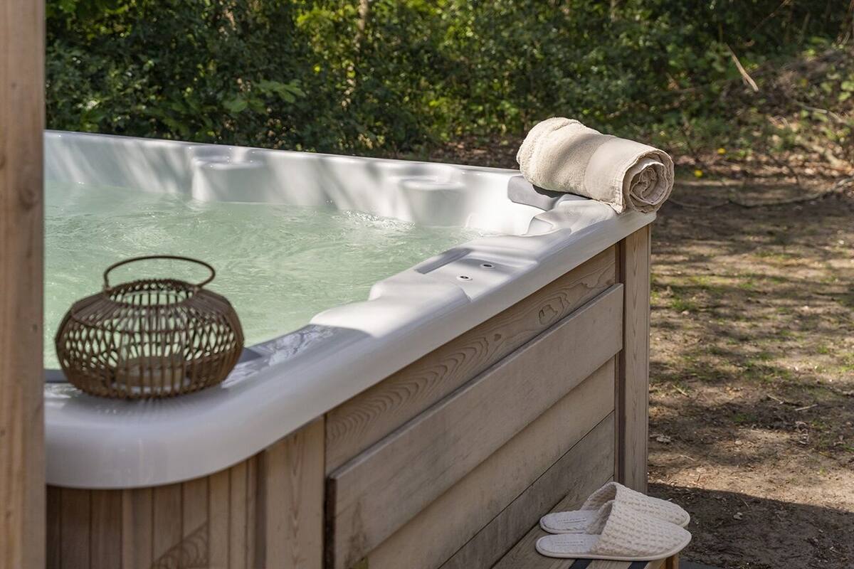 Un bain à remous en bois, avec une serviette et un panier tressé.