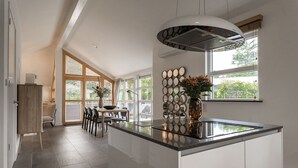 A modern kitchen with a central island, large windows, and a dining area with a view. - Suitelodges Gooilanden (Loosdrecht)