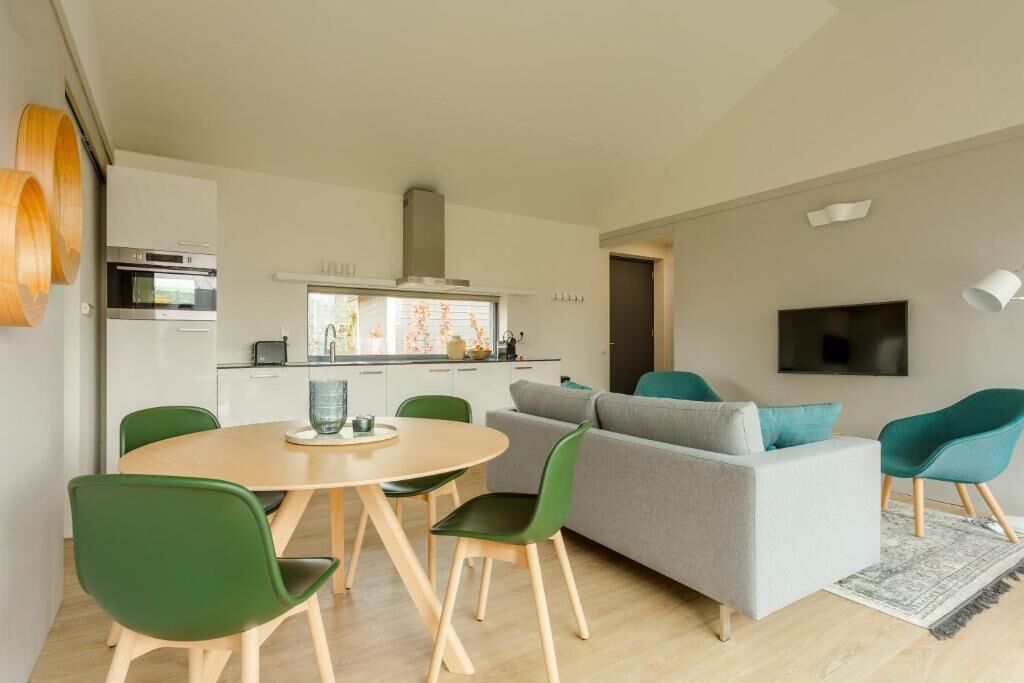 Un espace de vie moderne comprenant un coin repas, une cuisine et un canapé gris agrémenté de coussins turquoise.