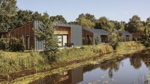 A modern house with a large window, a door, and a small outdoor seating area. - Suitelodges Gooilanden (Loosdrecht)