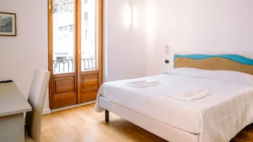 Ein Schlafzimmer mit Bett, Schreibtisch und einer Tür, die auf einen Balkon führt.
