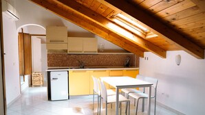 A kitchen with a white refrigerator, a dining table with chairs, and a wooden ceiling. - Residenza Ester (Amalfi)