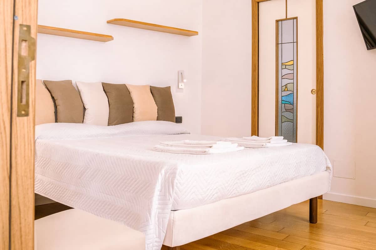 A neatly arranged bedroom with a bed, bedside tables, and a mirror.