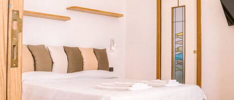 A neatly arranged bedroom with a bed, bedside tables, and a mirror.