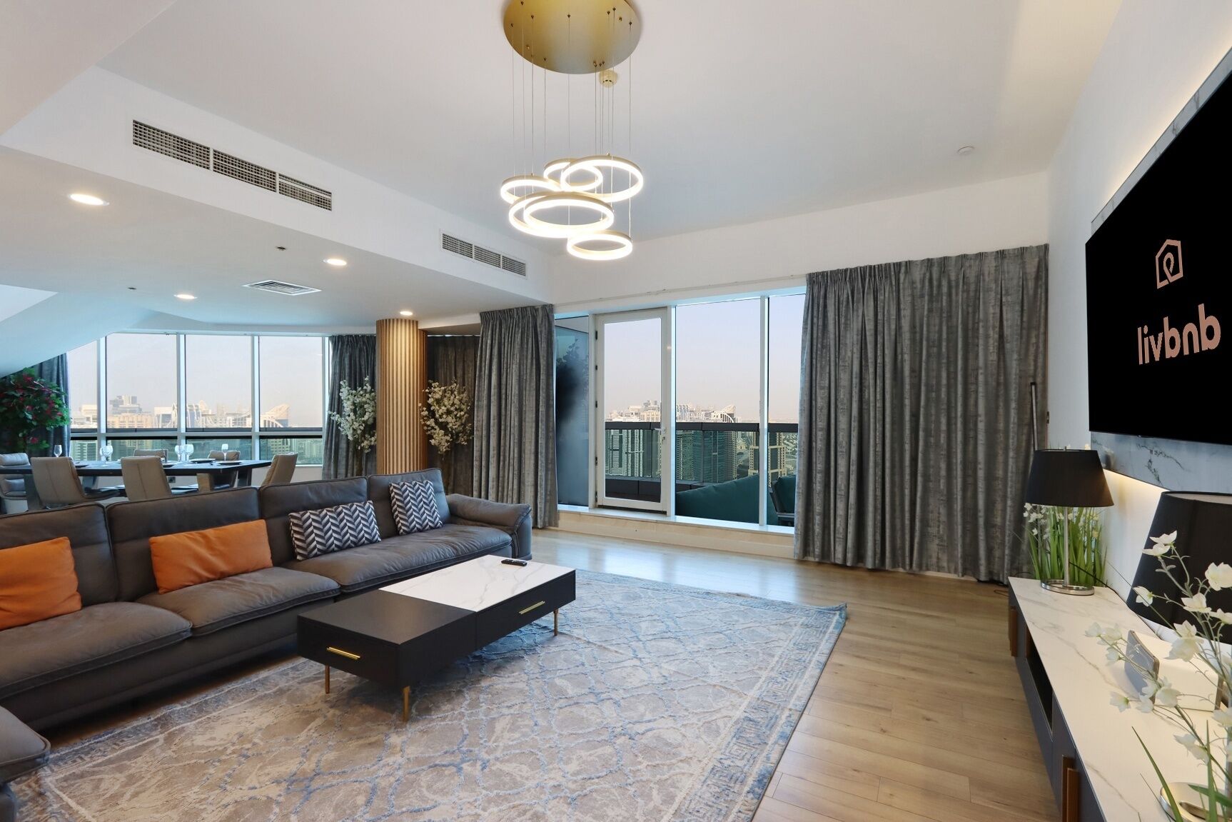 Una sala moderna con un sofá modular, una mesa de centro y un amplio ventanal con vistas a la ciudad.