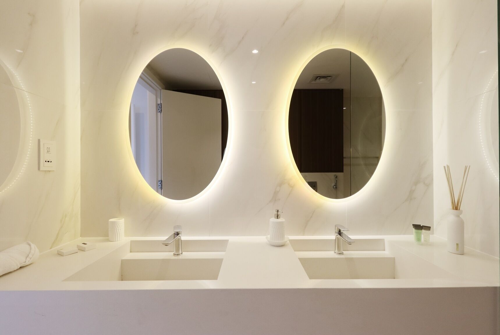 Une salle de bain moderne avec deux lavabos, un grand miroir et des toilettes.