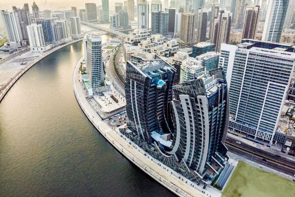 A high-rise building with a curved facade, located adjacent to a river.