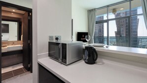 Et moderne hotelværelse med tekøkken, stort vindue med byudsigt og minibar.