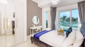 Een moderne hotelkamer met een bed, bureau, spiegel en uitzicht op palmbomen door het raam.