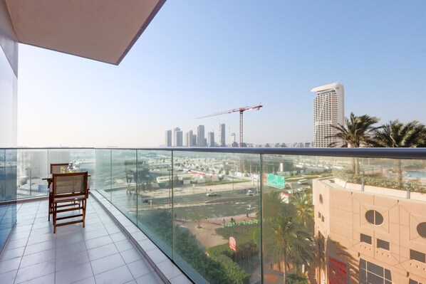 A balcony with a view of a cityscape, including high-rise buildings and a construction crane.