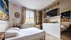 Une chambre à coucher avec un lit, un bureau, une télévision et une fenêtre avec des rideaux.