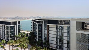 Un edificio moderno con varios pisos, amplios ventanales y vistas al mar y al horizonte de la ciudad.