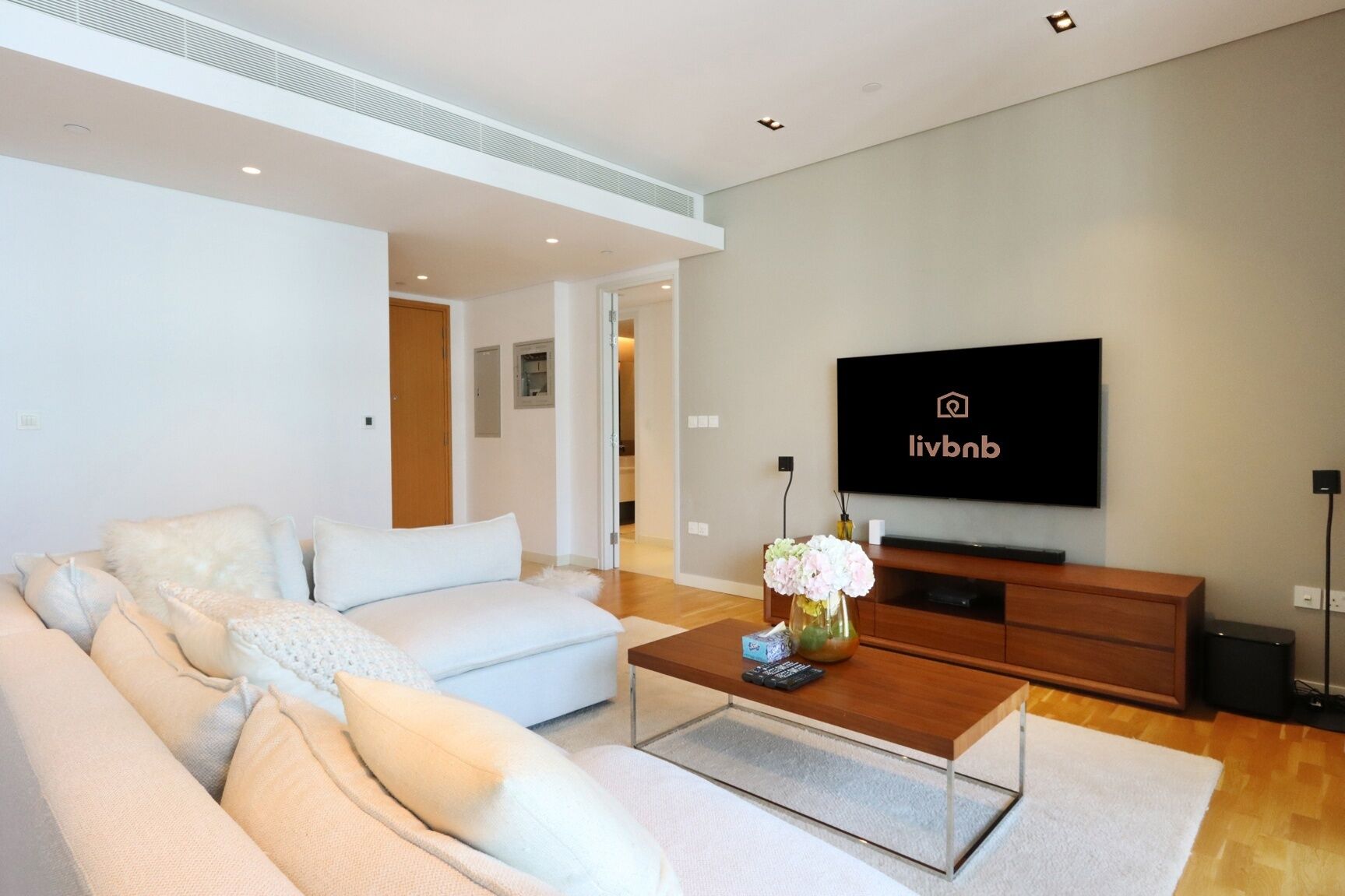 Ein modernes Wohnzimmer mit einer Couch, einem Couchtisch und einem an der Wand montierten Fernseher.