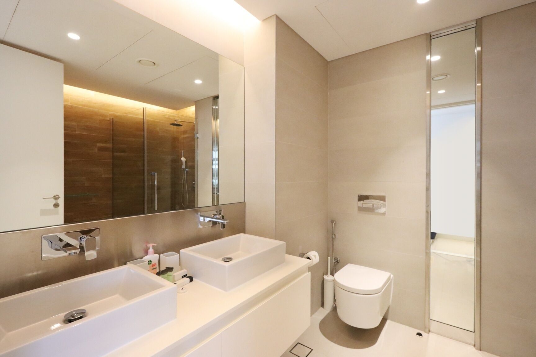 Een moderne badkamer met twee wastafels, toilet en een douchecabine van glas.