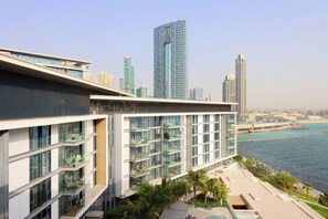 Un edificio moderno con varios balcones que dan a un cuerpo de agua y el horizonte de una ciudad.