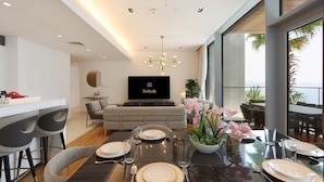 Una sala de estar moderna con comedor, un televisor de pantalla plana y un balcón con vistas.