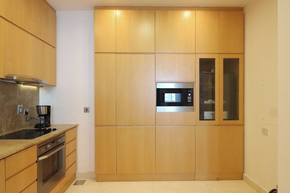 A modern kitchen with wooden cabinets, a built-in oven, and a microwave.