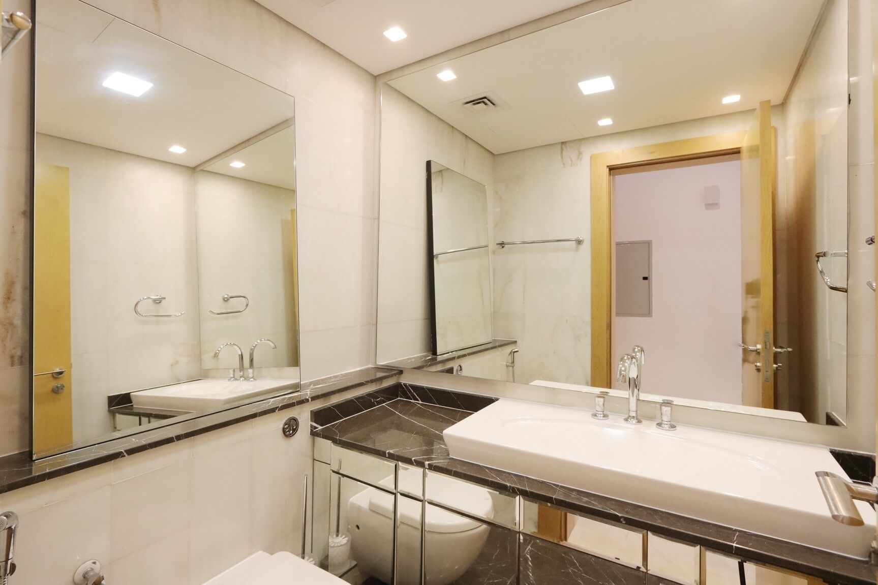 A modern bathroom with two sinks, a large mirror, and a shower area.