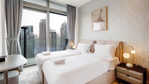 Een hotelkamer met twee bedden, een bureau en uitzicht op de stadshemel.