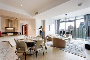 Un salon moderne comprenant un coin repas, un canapé et une grande fenêtre donnant sur la ville.