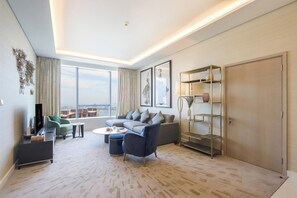 Ein modernes Wohnzimmer mit einer Couch, Sesseln, einem Couchtisch, einem Fernseher und einem Bücherregal.