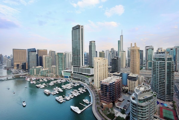 A marina with boats, a city skyline with modern high-rise buildings, and a clear sky.