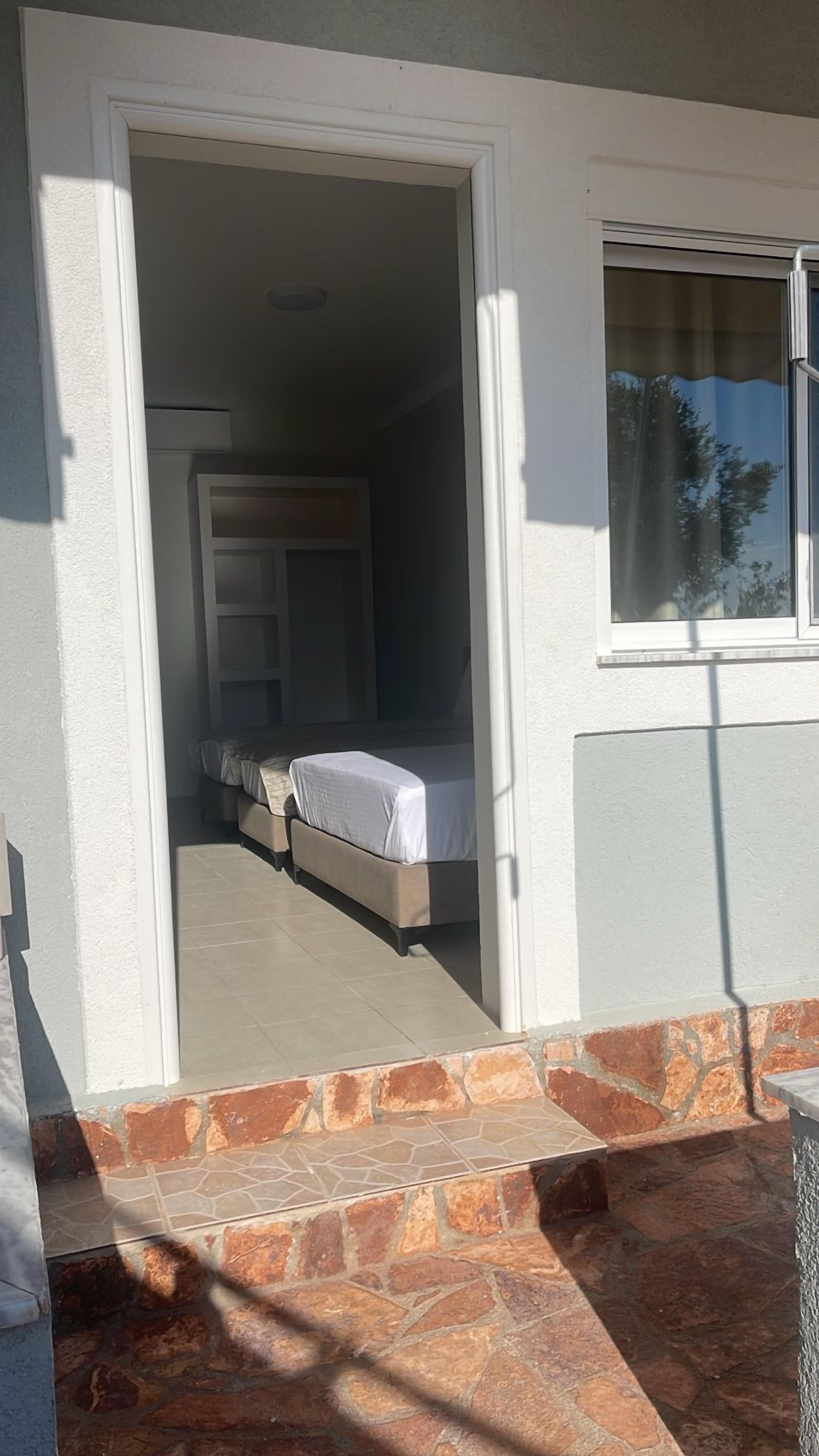 Una habitación con una cama, una ventana y una puerta que da a otra estancia.