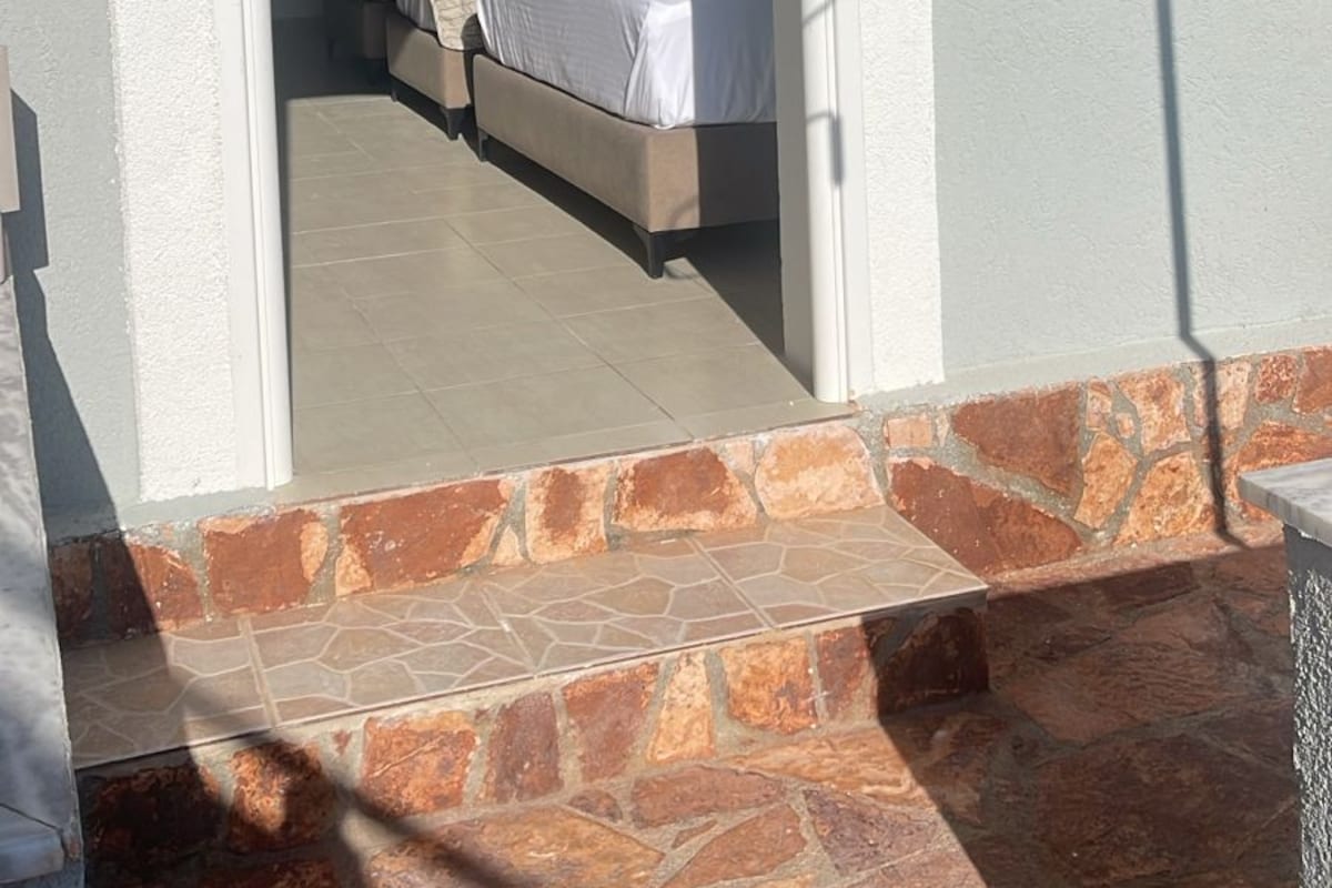 A room with a bed, a window, and a door leading to another room.