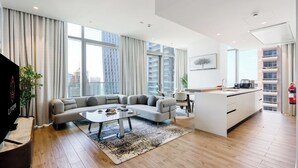 Una sala de estar moderna con un sofá, una mesita de centro y vistas de la ciudad a través de grandes ventanales.