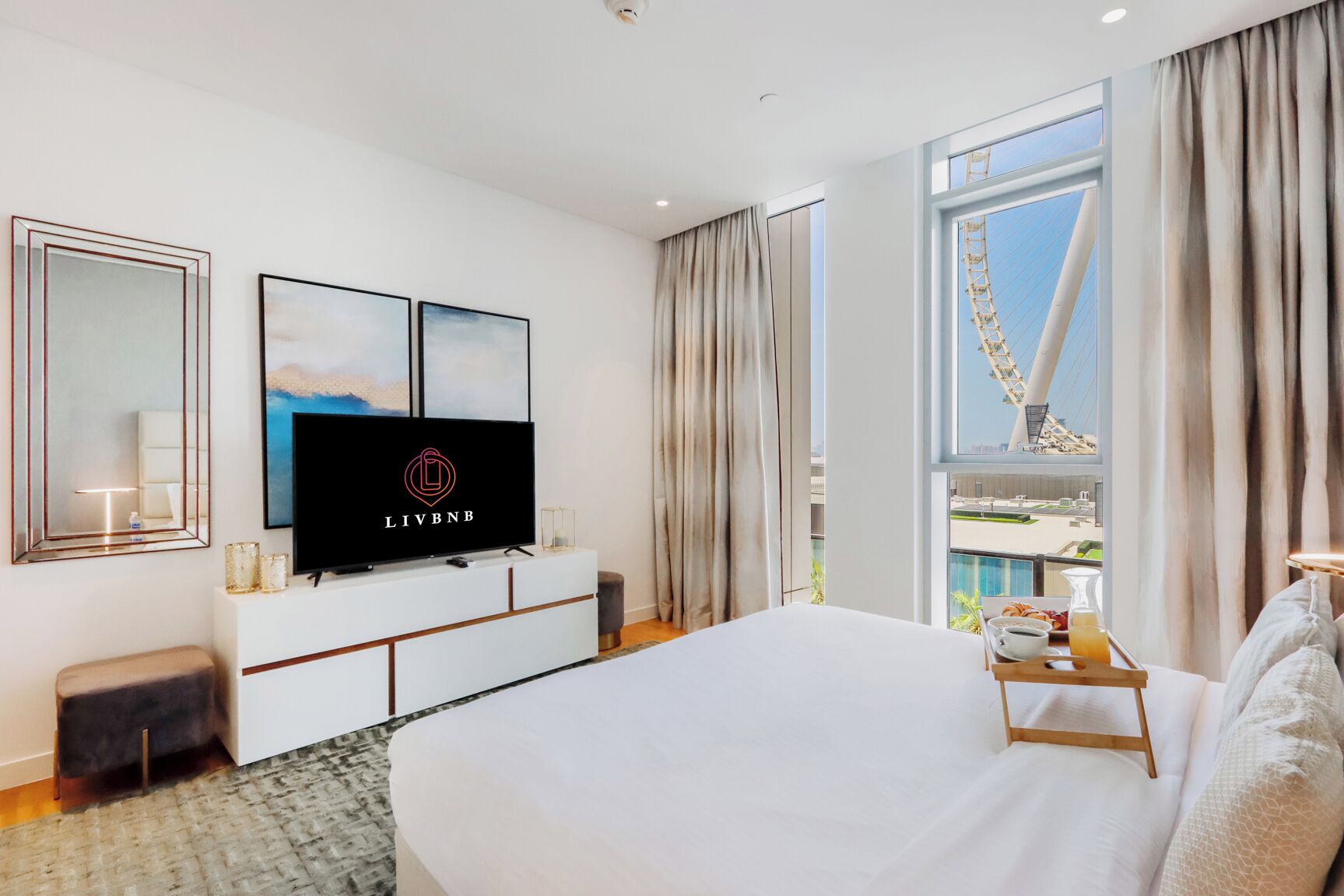 Una moderna camera d'albergo con un grande letto, una TV a schermo piatto, un balcone con vista su un ponte e sullo skyline della città.