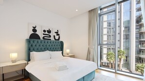 Et moderne hotelværelse med en stor seng, udsigt over byen og kunst på væggen.
