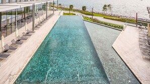En aflang, smal swimmingpool med klart vand, omgivet af moderne arkitektur og havudsigt.