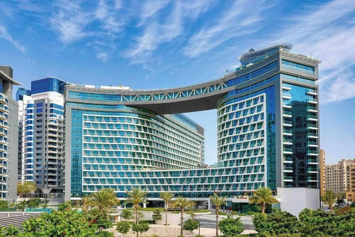 A modern hotel with a distinctive curved glass facade and a prominent overhanging structure.