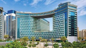 Un hotel modern amb una façana de vidre corba i una estructura prominent que sobresurt.