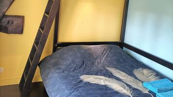 A bunk bed with a patterned bedspread, wooden beams, and a globe hanging from the ceiling.